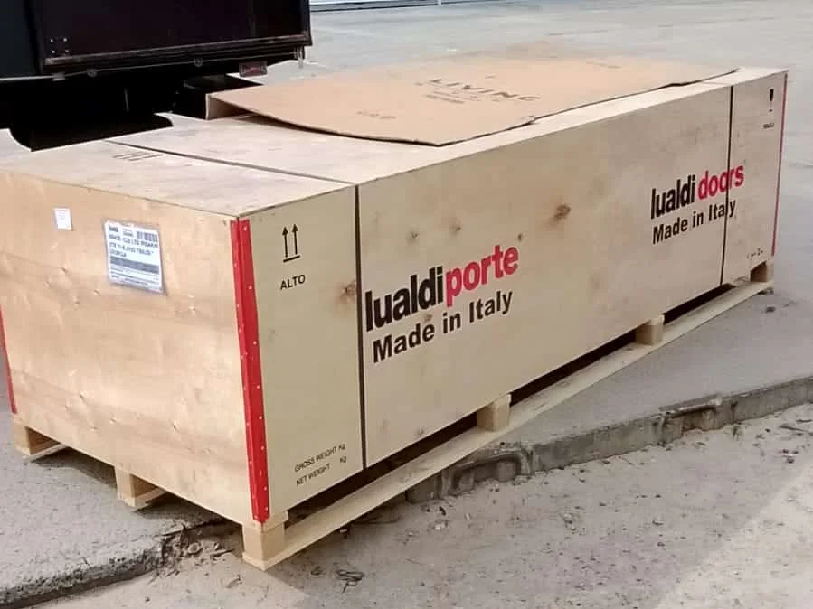 Двери Lualdi из Италии в заводском деревянном ящике на поддоне рядом с грузовиком на нашем складе